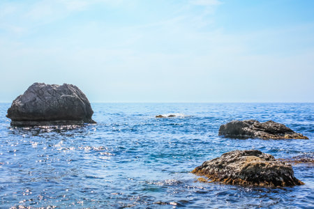 Sea with big rock stonesin the sunnt day. A beautiful cloudless morning at the sea. Clear waterの写真素材