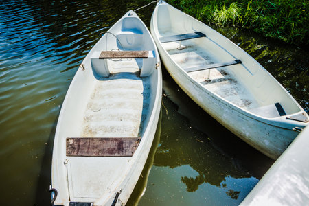 White pleasure boats at the pier on a small river in the city park. summer day. A cluster of...
