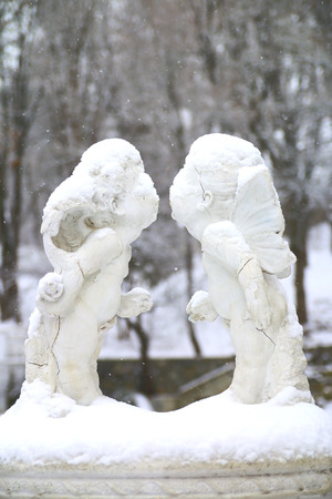 The photo depicts a statue of two lovers of Angels. This installation is set in an urban park in Kamenetz-Podolsk in Ukraine. Falling snow and gradually covers parts of the statue.の写真素材