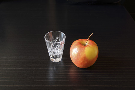 In the picture still-life with a glass of apple and bright on a dark background. The background of the wooden surface of black oak.の写真素材