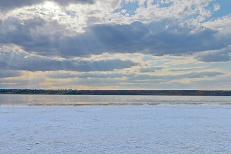 The photo was taken in Ukraine, in Odessa region. In the picture, the shore of a salty estuary covered with a crust of salt, like snow. A picturesque cloudy sky is visible above the estuary.の写真素材