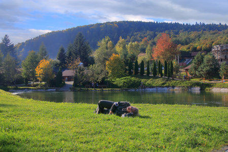 The photo was taken near the city of Truskavets in the Carpathians. In the picture, a young woman is resting on a green lawn near a mountain lake.の写真素材