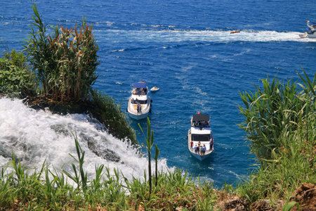 The photo was taken in Turkey. The picture shows a boat with tourists looking at a waterfall in the city of Antalya.の写真素材