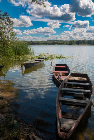 The photo was taken in Ukraine. The photo shows old fishing boats moored near the shore of the Southern Bug River on a summer day.の写真素材