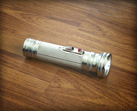Old metal flashlight torch on the floor laminate .の写真素材