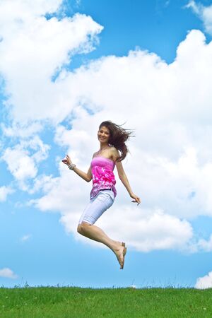 A young lady jumping on the background of the skyの写真素材