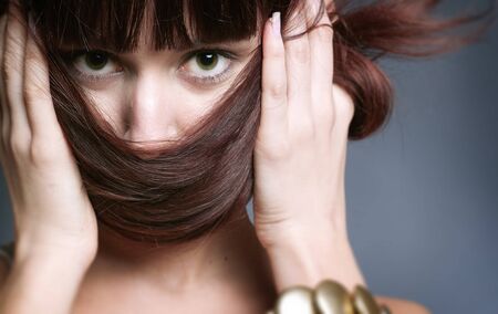Portrait of young woman with brown hair on a grey backgroundの写真素材