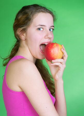 Portrait of young beautiful woman with apple on a green backgroundの写真素材