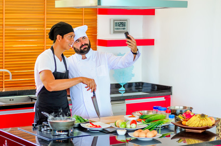 Colleagues at work: Thai and European chefs at the kitchen doing Thai foodの写真素材