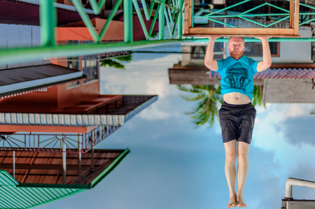 Turned upside down picture: yoga teacher portrait. Red hair man with a red beard showing headstand