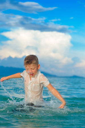 As if a bird: a close-up portrait of a handsome boy in wet slim fit shirt jumps and flutters over the water, a lot of splashes and funの写真素材