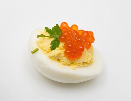 Egg with red caviar and parsley on a white background の写真素材