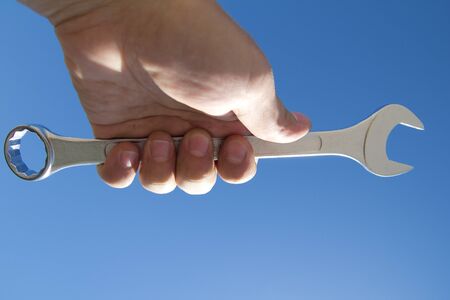 Hand with a wrench on a background of the sparkling sky.