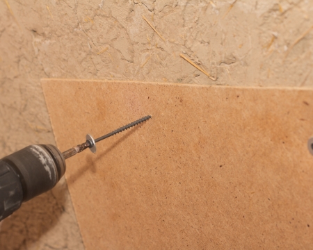 tightening the screws into the wood wallの写真素材