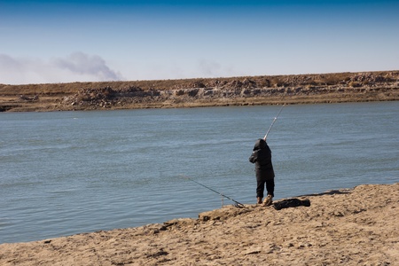 fisherman catching a fish on a fishing tackle in the riverの写真素材