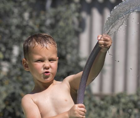 boy squirting water from a hoseの写真素材