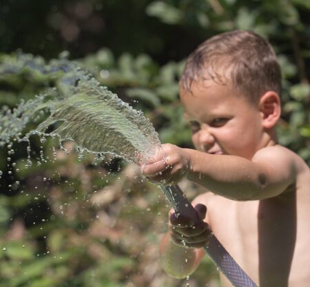 boy squirting water from a hoseの写真素材