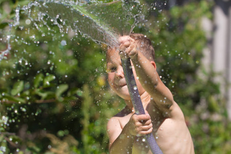 boy squirting water from a hoseの写真素材