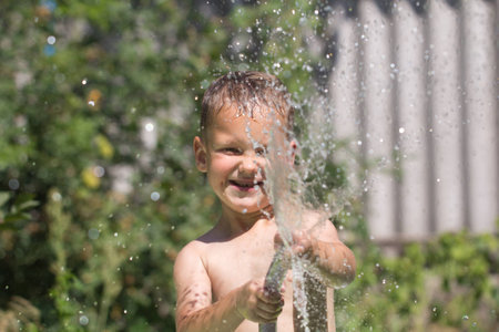 boy squirting water from a hoseの写真素材