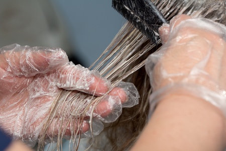 beautician applying hair dye on female customer's hairの写真素材