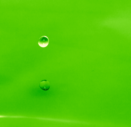 a drop of water falls into the green waterの写真素材