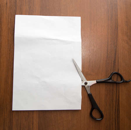 white sheet of paper with scissors on the wooden backgroundの写真素材