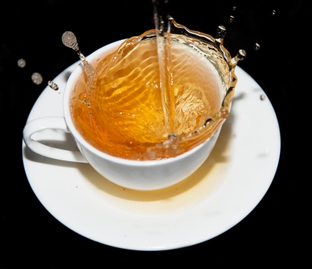 tea saucer with splashes on a black backgroundの写真素材