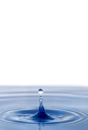 a drop of water falling in blue waterの写真素材
