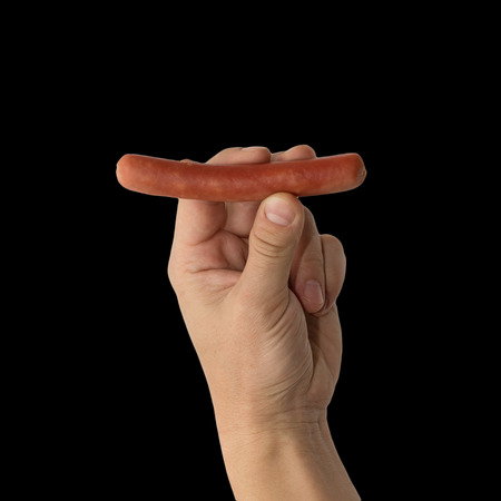 Sausage in a hand on a black backgroundの写真素材