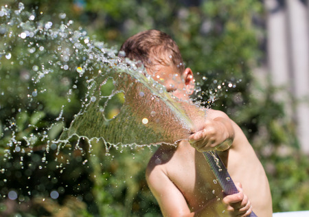boy squirting water from a hoseの写真素材