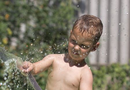 boy squirting water from a hoseの写真素材