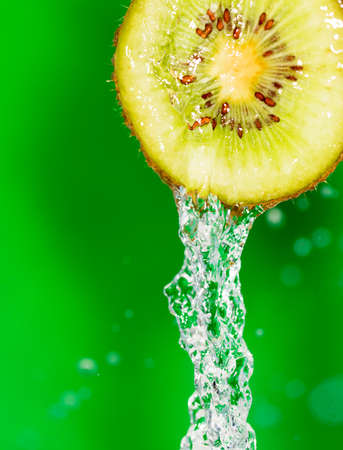 kiwi fruit in a spray of water on a green backgroundの写真素材