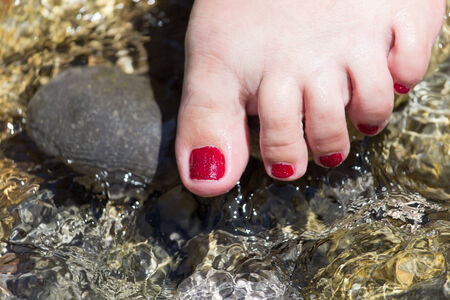 pedicure on foot in the water on the rocksの写真素材