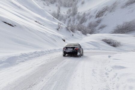 road with a car in winter in the mountainsの写真素材