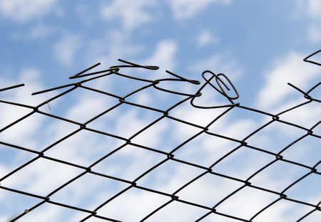 Metal fence against the blue sky with cloudsの写真素材