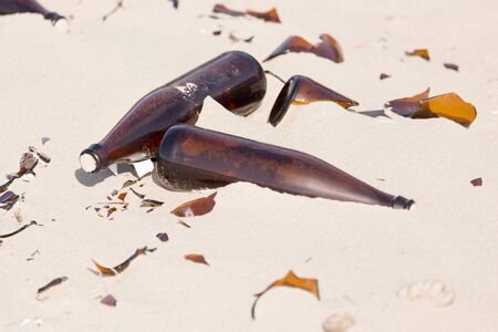 Glass bottles in the sand on nature. trashの写真素材