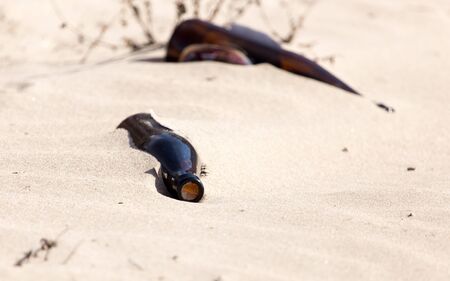 Glass bottles in the sand on nature. trashの写真素材