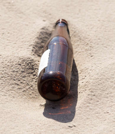 Glass bottles in the sand on nature. trashの写真素材