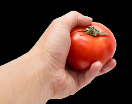 tomato in hand on a black backgroundの写真素材