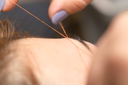 Grooming the eyebrows thread in a beauty salon. closeの写真素材