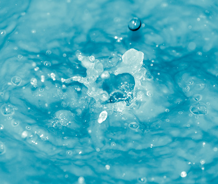 Drops of water falling into blue waterの写真素材