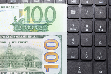dollars and euros on a laptop keyboardの写真素材