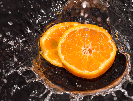 Orange in water splashes on a black backgroundの写真素材