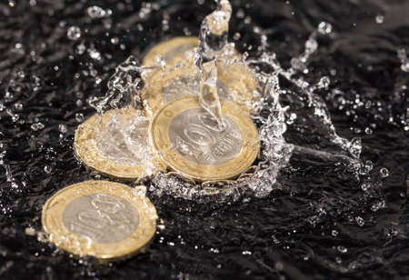 coins in water splashes on a black backgroundの写真素材
