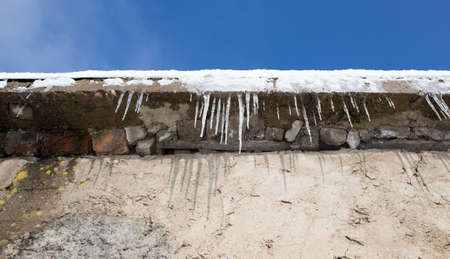 Large icicles hanging on the roof of the house in springtimeの写真素材