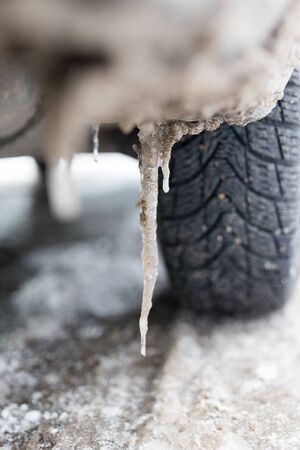 Snowy winter road with tire tracks in snow and tire and iciclesの写真素材