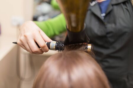 Hairdresser dries the hair dryer blond  hairの写真素材