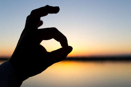 silhouette of the hand on the sunset backgroundの写真素材