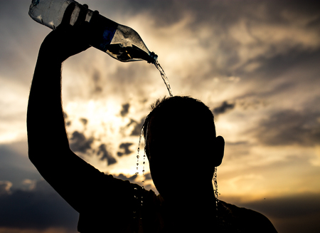 man pours water on his head in the sunsetの写真素材