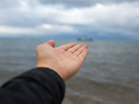 man's hand on a background of the sea with cloudsの写真素材